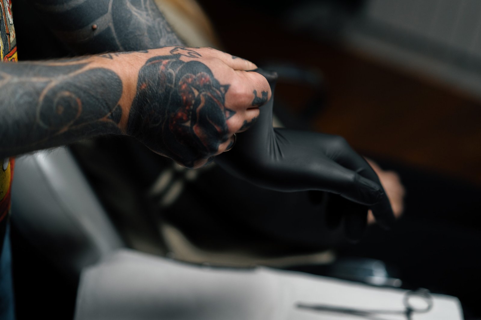 Tattoo artist in black gloves opening a sealed needle cartridge